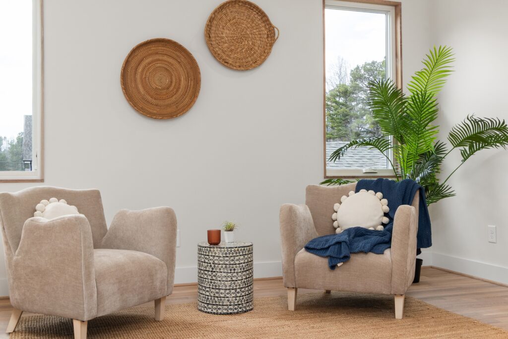 Two armchairs angled toward each other beside a small table in a bright, calm room, representing a conversation about PTSD treatment options